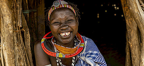 a smiling woman from the toposa tribe with beauty marks on her face